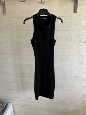 Svart ribbad klänning FB Sister XS - En svart, ribbad kortklänning från FB Sister i storlek XS. Klänningen är ärmlös med rund halsringning och har en slim passform som framhäver figuren. Perfekt för dig som gillar enkel och stilren design.