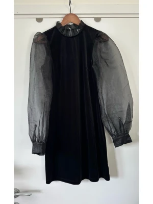 & Other Stories - Svart kort klänning med puffärmar - storlek S - Härlig svart klänning från & Other Stories i storlek S. Cool modell med långa, puffiga ärmar i organza och en hög krage med volangdetaljer. Klänningen har en nyckelhålsöppning baktill som försluts med en knapp. Halv-elastiskt sammetsmaterial som följer kroppen för en smickrande passform. Vacker festklänning som passar till alla fina tillfällen. Nypris 990:-. Mycket gott skick, som ny!