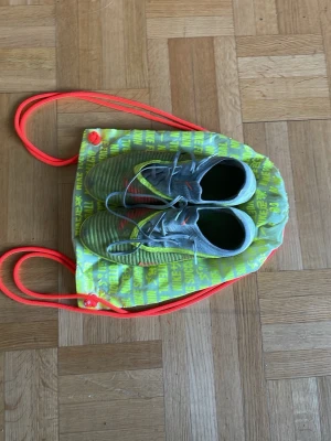 Gula Nike fotbollsskor elite  - Säljer ett par gula Nike fotbollsskor. Skorna har en modern, strömlinjeformad design och kommer med en matchande Nike-påse i gult och orange. Perfekta för dig som vill sticka ut på planen!