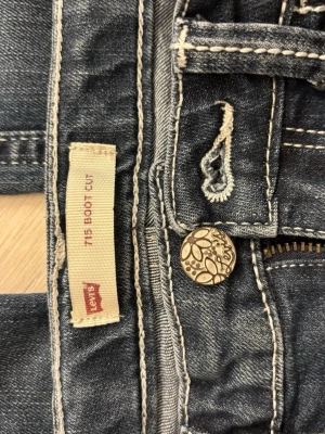 Levi's 715 Bootcut jeans blå - Säljer ett par klassiska blå Levi's 715 Bootcut jeans med snygga dekorativa bak fickor. Dessutom är de i bra skick! För referens är jag 153 cm lång och de passar perfekt i längden. Meddela ifall du har någon fråga. (Det går att förhandla priset 😊)