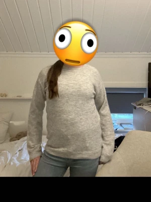 Ljusgrå stickad tröja - En basic ljusgrå stickad tröja med rund hals och långa ärmar. Tröjan har en enkel och stilren design som passar till det mesta. Perfekt att slänga på sig när det är kyligt ute. Materialet ser ut att vara mjukt och bekvämt.