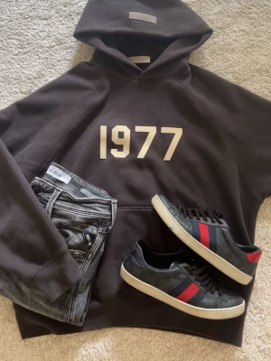Essentials hoodie - Snygg essentials hoodie i mörkgrå färg med trycket '1977' i vitt på bröstet. Knappt använd eftersom att den är för stor för mig! Storlek xs men sitter som en S