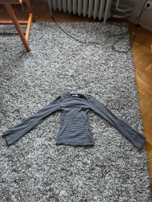Randig långärmad topp från Weekday - Säljer en svart och grå långärmad topp från Weekday i storlek XS. Toppen har smala horisontella ränder och är gjord i mjuk bomull. Ärmarna är utsvängda.