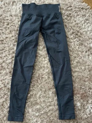 Gråa impact leggings DFYNE - Impact tights i färgen ”slate grey” från DFYNE med låg midja och tight passform. Tillverkade i stretchigt material som passar perfekt för gym och träning. Diskret logga vid linningen och stilren design.