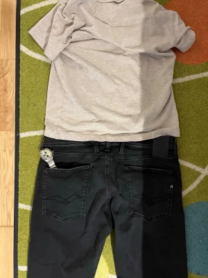 Replay anbass  hyperflex  - Ny Knappt använda Replay Anbass-jeans med fina blekningar. Det här är en väldigt unik modell med en trådad Replay-fågellogotyp på bakfickorna och en glänsande Replay R-logotyp på höger bakficka.  Midjan är lös vilket ger mer utrymme runt höfterna.