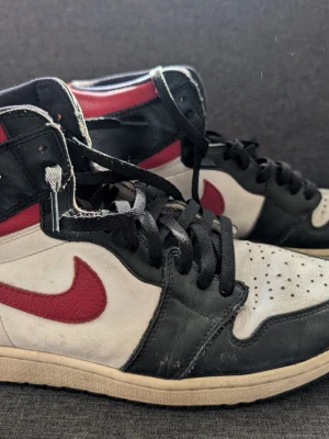 Nike Air Jordan 1 High "Chicago", stl 46 (US 12) - Nike Air Jordan 1 High i den ikoniska "Chicago"-färgställningen. Stl EU 46 / US 12. Använda och det syns - en del veck och slitage på bilderna, prissatt därefter.