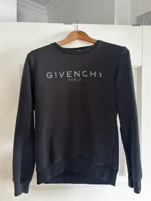 Svart sweatshirt från Givenchy - Stilren svart sweatshirt från Givenchy med tryckt logga på bröstet. Tröjan har rund halsringning, långa ärmar och ribbade muddar vid ärmslut och nederkant. Perfekt för en avslappnad och trendig look. Pris kan diskuteras!