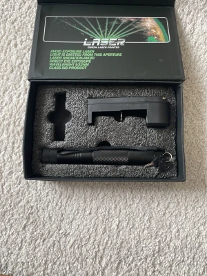 Grön laserpekare i presentförpackning - Säljer en grön laserpekare med svart metallhölje, levereras i en snygg presentförpackning. Medföljer gör även ett laddningsbart batteri och laddare. Perfekt för presentationer, astronomi eller experiment. Enkel att använda och smidig att ta med.