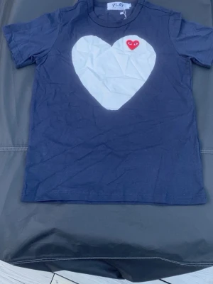 Mörkblå t-shirt med hjärtdetalj - Comme des gracons t shirt i mörkblå färg i storlek M.