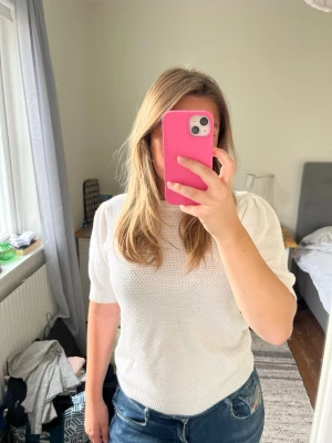 Vit stickad topp med kort ärm - Säljer en fräsch vit stickad topp med korta ärmar och rund hals. Tröjan har en diskret strukturstickning och ribbade muddar vid ärmslut och nederkant. Från vila, andvänd 3 gånger.