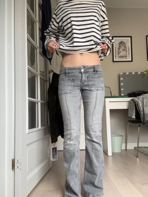 Grå bootcut low rise jeans - Snygga grå bootcut low rise jeans med markerade sömmar och stora fickor framtill. Dom e från Gina trikot, i nytt skick använt dom få antal gånger och dom e i xs!
