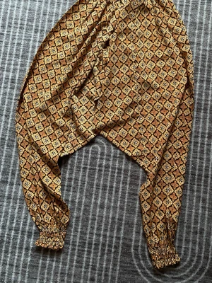 Mönstrad jumpsuit storlek 134/140 - Säljer en jumpsuit unikt mönster i bruna och beige toner. Perfekt för dig som gillar boho-vibbar och vill sticka ut lite extra.