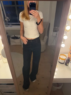 Mörkblå raka jeans med hög midja - Säljer ett par mörkblå jeans med rak passform och hög midja. Jeansen har klassiska fem fickor och stängs med knapp och dragkedja. Perfekta till en enkel t-shirt eller hoodie för en avslappnad look.