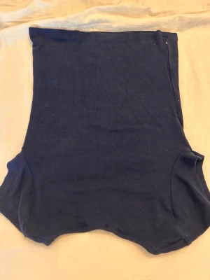 Mörkblå body från Gina Tricot - Säljer en enkel och stilren mörkblå tröja från Gina Tricot. tröja  har en ärmlös design och är tillverkad i ett mjukt, stretchigt tyg som sitter skönt mot kroppen. Perfekt att matcha med jeans eller kjol för en clean look, den är urringad upptill och i ett bra skick inte så använd men har haft den ett tag därför ett lite lägre pris