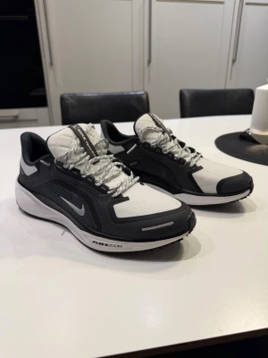 Nike gråvita sneakers Pegasus 41 GORTEX - Snygga svartvita Nike sneakers med Air Zoom-sula och GORE-TEX-detaljer. reflekterande detaljer och klassisk Nike-logga på sidan. Perfekta för dig som gillar sportig stil och vill ha bekväma sneakers.