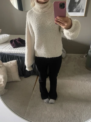 Stickad vit tröja med krage  - Mysig stickad polotröja i offwhite med breda ballongärmar och ribbade muddar. Tröjan har en hög, tjock polokrage och är gjord i ett fluffigt material som känns riktigt skönt. Perfekt för kalla dagar och enkel att styla till olika outfits. Den är som en S 