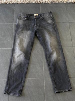 grå/svarta Jeans från Jack&Jones 30/30, oanvända - Jeans från Jackk&Jones i grå tvätt, Storleken är 30/30. Helt oanvända då dom är lite för korta för mig. Passar bra om du är runt 175cm. Ny pris ligger runt 800kr. Ni ser dem på, på fjärde bilden. Jag i dem referens är 179cm