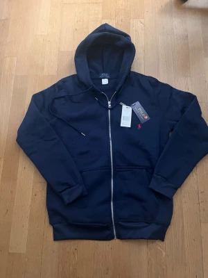 Mörk blå polo Ralph lauren zip tröja  - Polo Ralph Lauren tröja – mörkblå, S  Helt ny Polo Ralph Lauren tröja i mörkblå färg, storlek S. Aldrig använd, säljes endast eftersom den är för stor för mig.  📏 Storlek: S 🎨 Färg: Mörkblå ✨ Skick: Helt ny