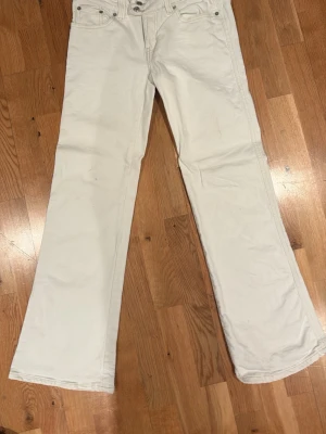 Vita bootcut jeans med brodyr - Säljer ett par vita bootcut jeans med snygg brodyr på bakfickorna. Mindre fläckar som borde gå bort i tvätten.