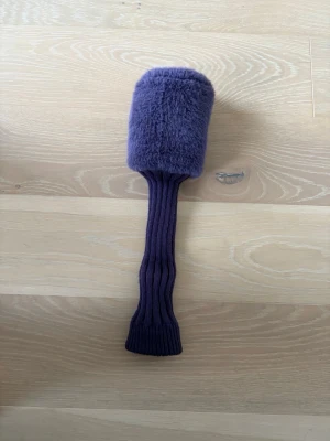 Lila headcover till golfklubba - Säljer ett lila headcover till golfklubba, med mjuk fluffig ovandel och ribbstickad socka. På toppen finns en silverfärgad siffra 3, vilket passar till en träklubba. Perfekt för att skydda klubban i bagen.