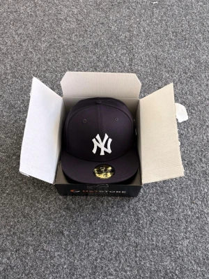 HELT NY! New Era keps - Säljer en svart New Era 59FIFTY keps med klassisk New York Yankees-logga i vitt framtill. Kepsen har rak skärm och broderade ventilationshål. Tillverkad i ett slitstarkt tyg som ger en clean och sportig look.