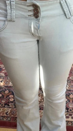 Ljusblå bootcut jeans med snörning - Säljer ett par ljusblå bootcut jeans med unik snörningsdetalj i midjan. Jeansen har klassisk femficksdesign och är tillverkade i ett stretchigt denimtyg som sitter snyggt. Perfekta för dig som gillar retrovibbar och vill sticka ut lite extra.
