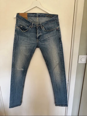 Dondup jeans - Snygga ljusblå jeans med slim fit passform och slitningar på benen. Klassisk femficksmodell med dragkedja och knapp i midjan. Jeansen har en tvättad look och raka ben, perfekta till en avslappnad stil. Slitningarna går ej igenom, skriv vid eventuella frågor, pris ej huggt sten