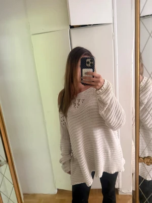 Oversized beige stickad tröja - Mysig oversized stickad tröja i beige med rund hals och dekorativt hålmönster upptill. Stl 48/50 som varierar på L 