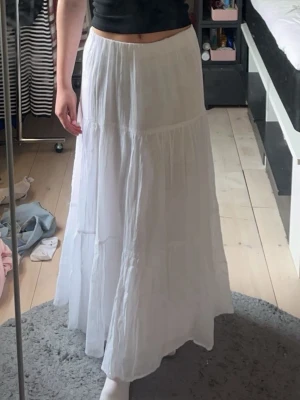 Vit långkjol  - Säljer en flowy vit långkjol i mjukt linnetyg/bommull. Kjolen har en luftig och lätt känsla med flera lager och en enkel, stilren design. Perfekt för varma dagar och enkel att matcha med olika toppar.