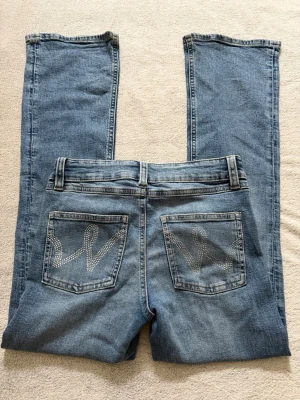 Ljusblå bootcut jeans med små nitar på bakfickorna från Gina Tricot - Snygga ljusblå bootcut jeans med dekorativa nitar i mönster på bakfickorna. 