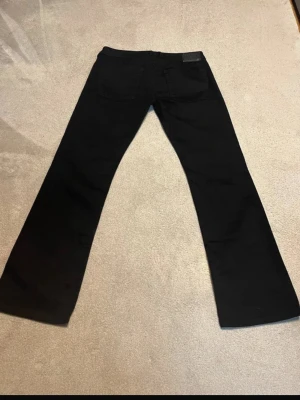 Svarta bootcut jeans - Säljer ett par svarta bootcut jeans med klassisk femficksdesign. Jeansen har raka ben som blir något vidare nedtill och är tillverkade i ett mjukt denimtyg. Perfekta för dig som gillar en tidlös och clean look.