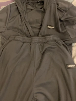 Grått loungewear-set från Mckenzie - Mysigt grått loungewear-set från Mckenzie med matchande hoodie och byxor. Setet har elastisk midja på byxorna och båda plaggen har diskreta logopatchar. Perfekt för chill dagar hemma. Materialet är mjukt och följsamt.