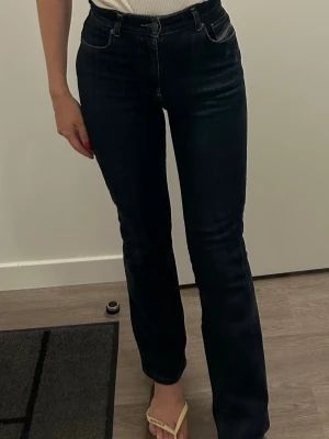Diesel raka jeans med hög midja - Snygga mörkblå jeans med raka ben och hög midja. Klassisk femficksmodell med knapp- och dragkedjestängning. Jeansen har en tidlös look och passar perfekt till en enkel topp eller hoodie. Från märket Diesel.