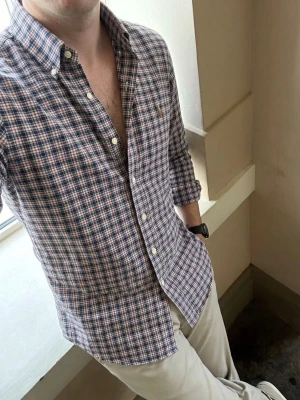 Ralph Lauren Skjorta - Säljer en klassisk rutig skjorta från Ralph Lauren i slim fit stretch oxford. Skjortan har lång ärm, knappar framtill och button-down krage. Färgerna är blå, grön, röd och vit. Perfekt för dig som gillar en tidlös och stilren look.