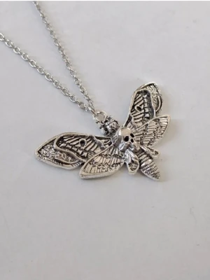 Silvrigt halsband med dödskallesvärmare  - dödskallesvärmare (ofta kallad "Death Moth" eller "Silence of the Lambs moth"). Det är ett populärt motiv. En fjäril med sitt fascinerande dödskalleliknande teckningen på ryggen. Materialet rostfritt stål.