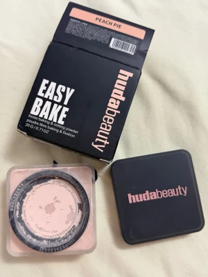 Huda Beauty Easy Bake Peach Pie puder - Löspuder från Huda Beauty i nyansen Peach Pie. Kommer i en fyrkantig burk med svart lock och rosa text. Perfekt för baking och att fixera foundation, ger en matt finish och har en lätt persikotonad färg. Använd en gång inte min färg 