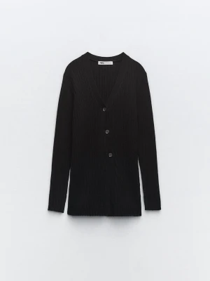Svart ribbad kofta från Zara - Stilren svart ribbad kofta från Zara med v-ringning och tre knappar framtill. Långärmad modell i mjukt material som passar perfekt till lager på lager. Enkel och tidlös design som funkar till det mesta.