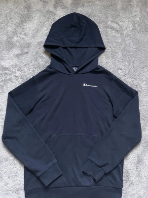 Champion Black Hoodie – XL (13/14 Years) – Excellent Condition - Classic Champion hoodie in black with embroidered Champion logo on the chest and sleeve.  ✔ Excellent condition ✔ Soft and comfortable material ✔ Kangaroo pocket ✔ Hooded design ✔ Size: XL (13/14 Years / 162–167 cm)  Perfect everyday hoodie that’s easy to style with jeans or joggers.  Feel free to message me if you have any questions or would like more photos. Fast shipping!