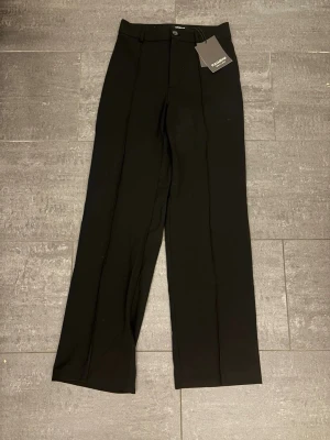 Svarta kostymbyxor Pull&Bear M - Stilrena svarta kostymbyxor från Pull&Bear Black Label. Byxorna har raka ben, hög midja och pressveck framtill för en clean look. Perfekta att matcha med en skjorta eller stickad tröja. Materialet känns mjukt och följsamt. Alldrig andvända prislappen kvar. Köpta för 379:- men säljes för 249:-. Pris kan diskuteras vid snabbare affär