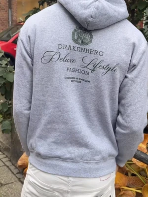 Grå hoodie drakenberg - Säljer en grå hoodie från drakenberg med grön patch på bröstet och även på ryggen. Har ett litet hål på ärmen som enkelt går att fixa. Den är helt oanvänd och kom med hålet, reklamerade och fick en ny. Hör av dig vid frågor elr liknande🙌