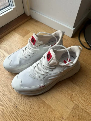 Vita sneakers från HUGO - Stilrena vita sneakers från HUGO med chunky sula och röda logodetaljer på plös och innersula. Väldigt bra skick 