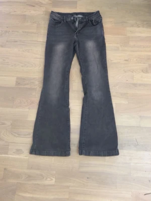 Grå bootcut jeans  - Säljer ett par grå bootcut jeans och klassisk femficksmodell. Jeansen har utsvängda ben och normal midja. Materialet är denim i bomull med lite stretch för skön passform.