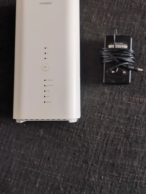 Vit Huawei mobil router med nätadapter - Huawei mobil router i stilren vit design med tillhörande svart nätadapter. Routern har LED-indikatorer för power, status, LAN, WiFi och mode. Perfekt för att fixa stabilt internet hemma eller på kontoret.