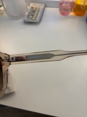 Beige solglasögon från CHIMI - Snygga solglasögon från CHIMI i transparent beige med fyrkantig form. Kommer med originaletui och putsduk. Designade i Stockholm och har mörka glas som ger en cool kontrast till den ljusa bågen.