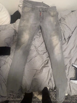 Ljusgrå skinny jeans från Dsquared2 - Säljer ett par ljusgrå skinny jeans från Dsquared2 med slitna detaljer och klassisk femficksmodell. Jeansen har låg midja och är tillverkade i stretchigt denim för en bekväm passform. Perfekta för en trendig streetstyle-look.