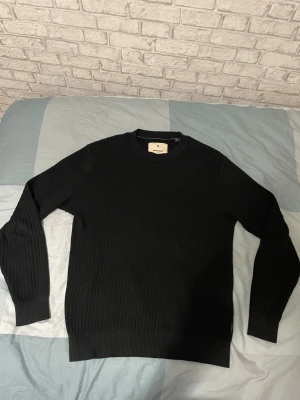 Jack n jones - Snygg svart ribbstickad tröja med rund hals och långa ärmar. Tröjan har en enkel och stilren design med ribbade muddar vid ärmslut och nederkant. Perfekt basplagg för garderoben och lätt att matcha till olika outfits.