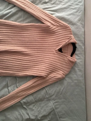 Beige ribbstickad tröja - Säljer en beige ribbstickad tröja med lång ärm och hög krage. Tröjan har en mjuk och stretchig känsla, perfekt för lager på lager. Passar dig som gillar en enkel men stilren look. Går att diskutera priset!