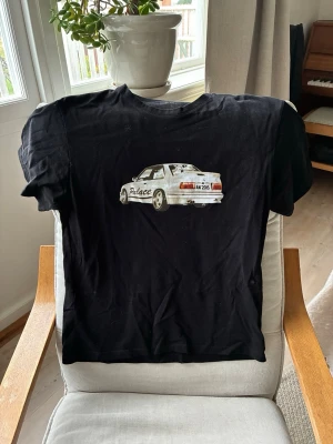 Svart t-shirt med biltryck - Svart t-shirt från Palace med ett stort tryck av en bil på framsidan. Klassisk passform och rund hals. Bara att höra av er vid frågor