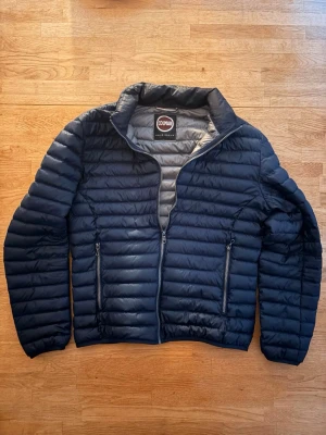 Colmar Jacka - Snygg mörkblå dunjacka från Colmar med quiltad design och två dragkedjeförsedda fickor framtill. Jackan har hög krage och grått innerfoder. Perfekt för kalla vinterdagar och har en modern, sportig look. Storlek L men skulle säga att den passar M. Skriv vid minsta funderingar 👍👍