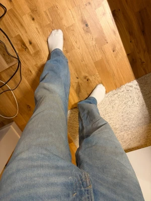 Ljusblå jeans - Säljer ett par ljusblå jeans med lite overzise passform och klassisk femficksdesign. Jeansen har normal midja och är tillverkade i ett mjukt denimtyg som ger en avslappnad look. Perfekta för dig som gillar en enkel och stilren stil.